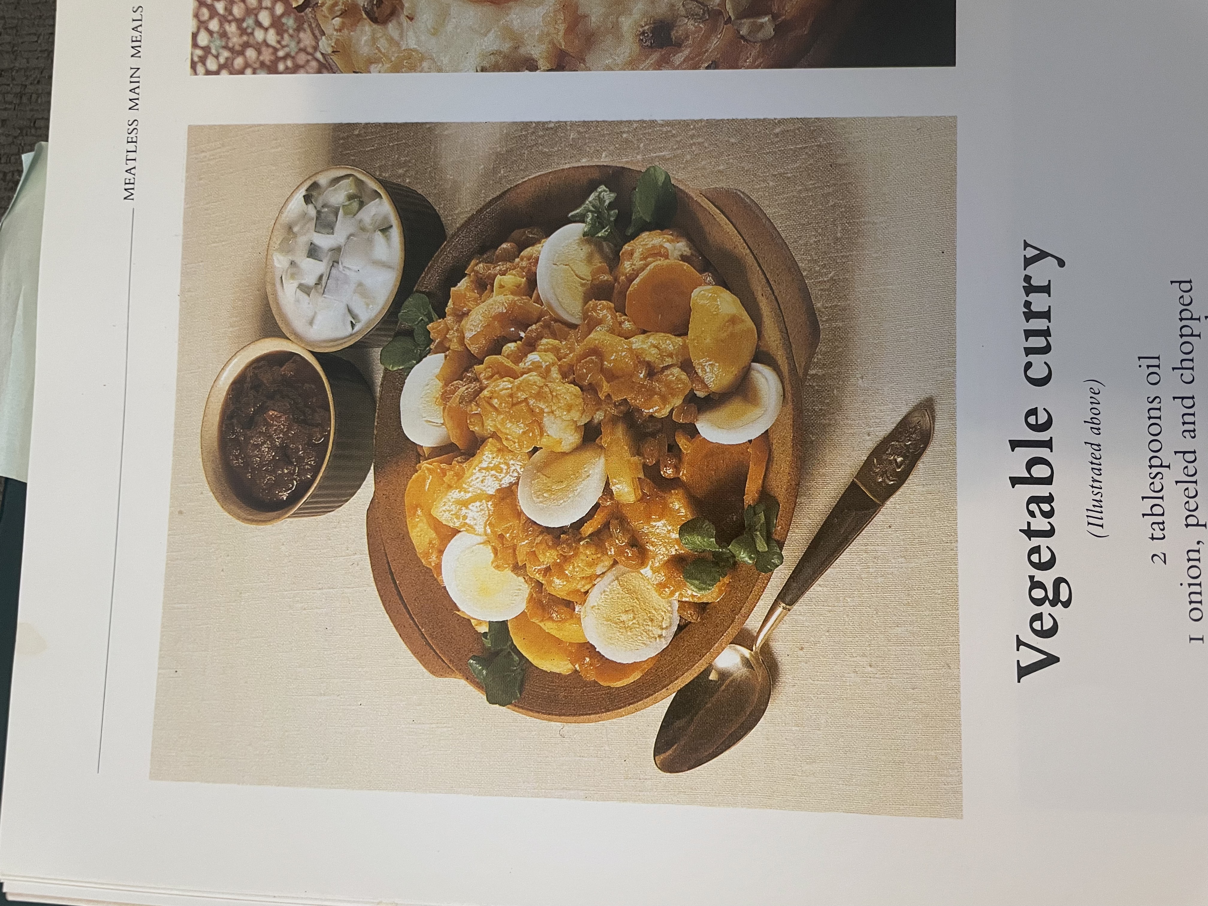 A cookbook photo of an Indian-style vegetable curry dish with sliced hard boiled eggs on top